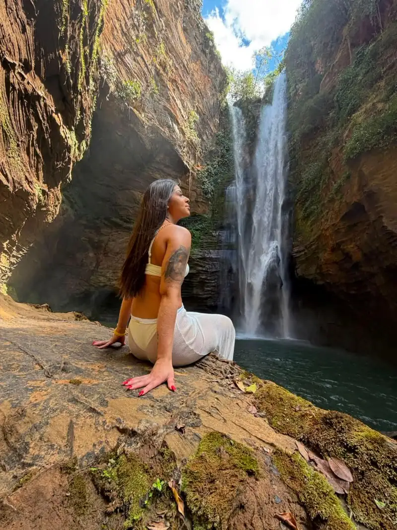 Viajante sentada na pedra diante da Cachoeira Santa Bárbara