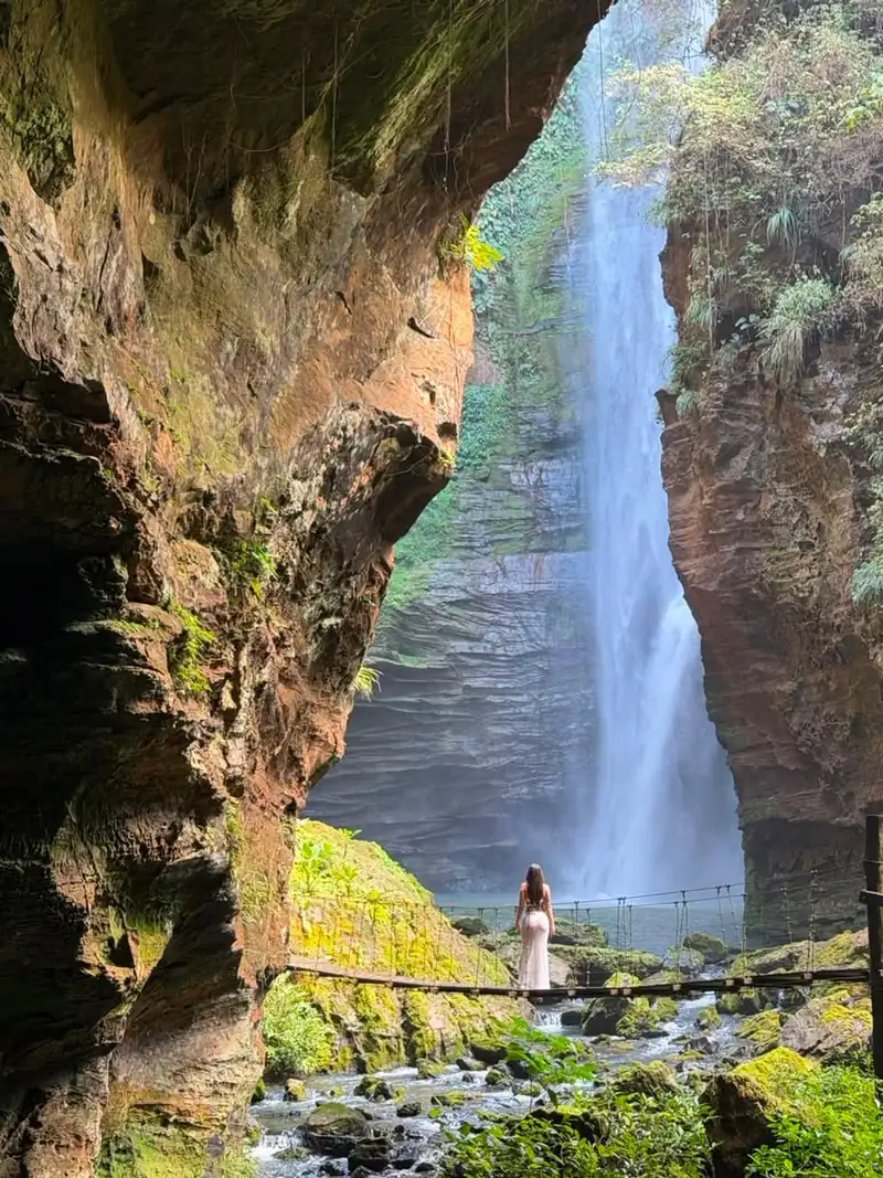 Viajante na ponte suspensa diante da cachoeira dentro do cânion da Pedra Caída